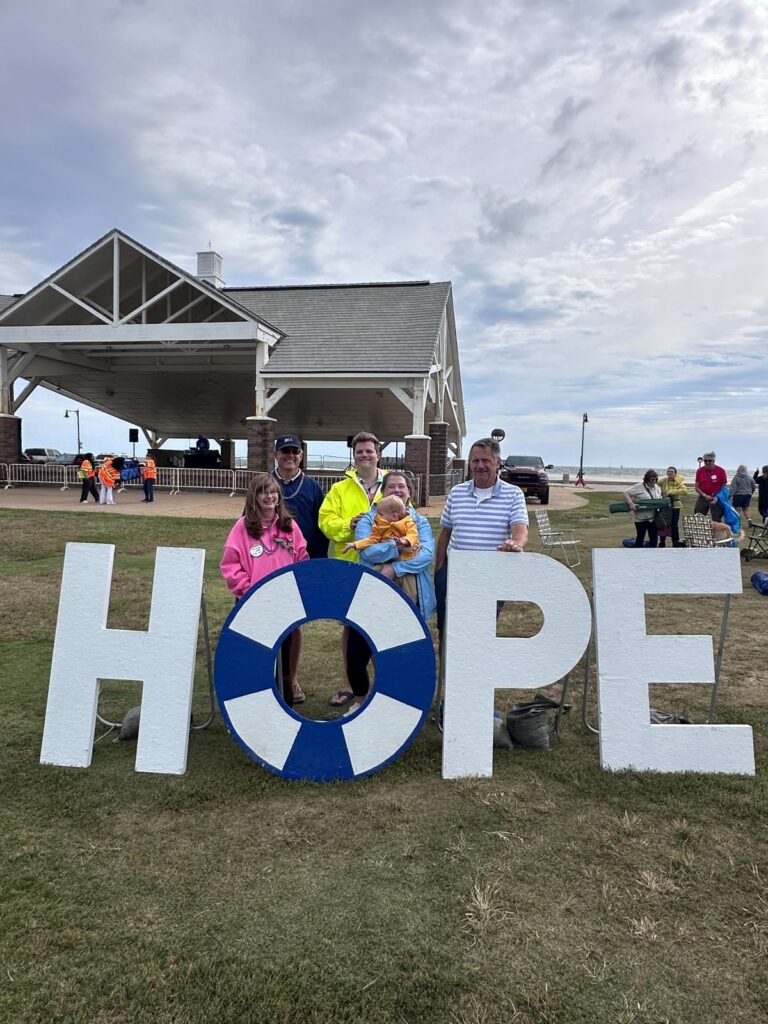 Artisan Counseling family and supporters standing behind the HOPE sign at the Virginia Peninsula Out of the Darkness Walk at Buckroe Beach