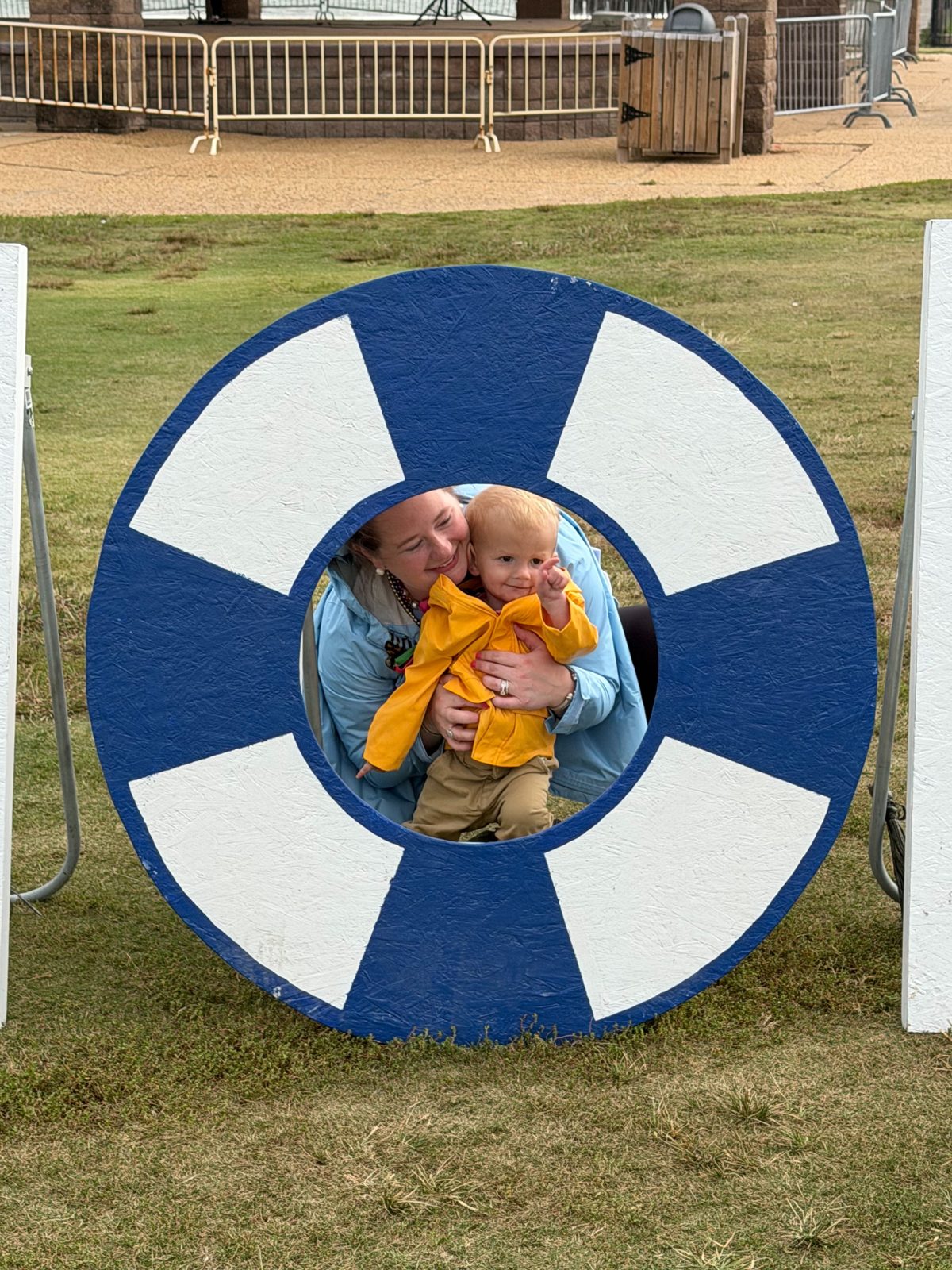 Abby Brundage, LCSW and her son posing through a life ring cutout at the Out of the Darkness Walk in Hampton, VA